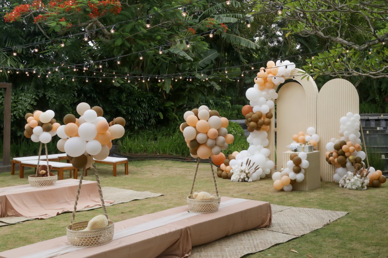 Garden celebration styled with neutral balloon arrangements and low picnic tables