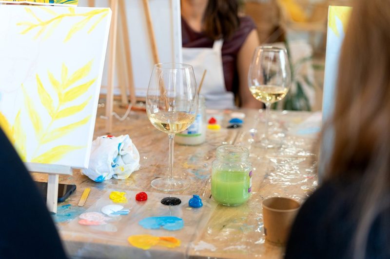 Guests painting at a creative workshop with wine glasses on the table